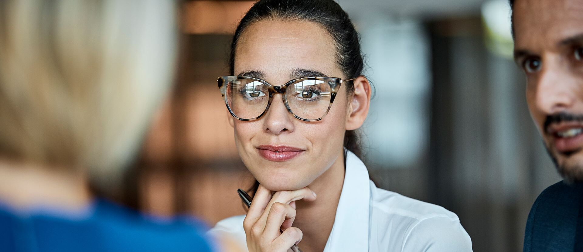 Smiling male colleague with glasses and smiling female colleague in an office, team working behind