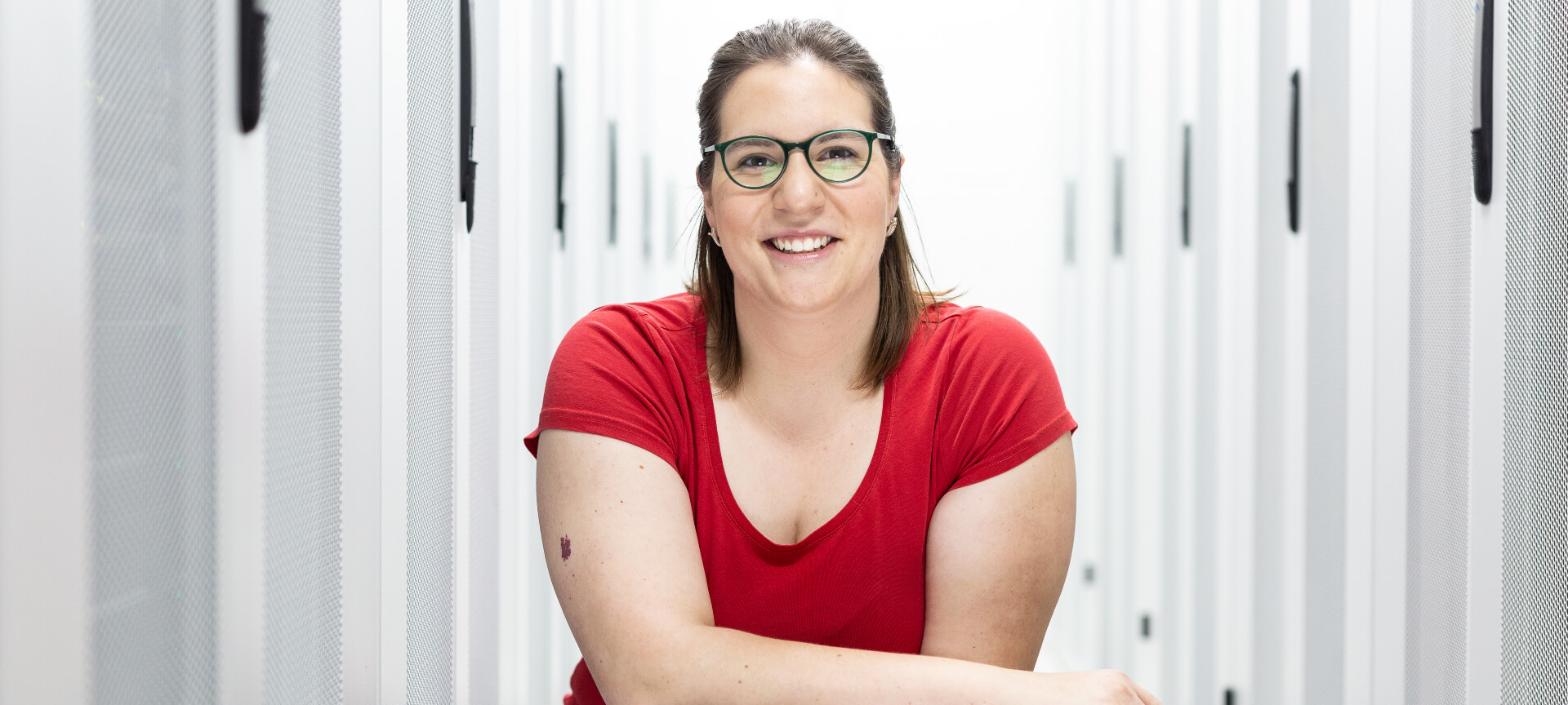 Smiling United Internet employee with glasses in a server room between server racks