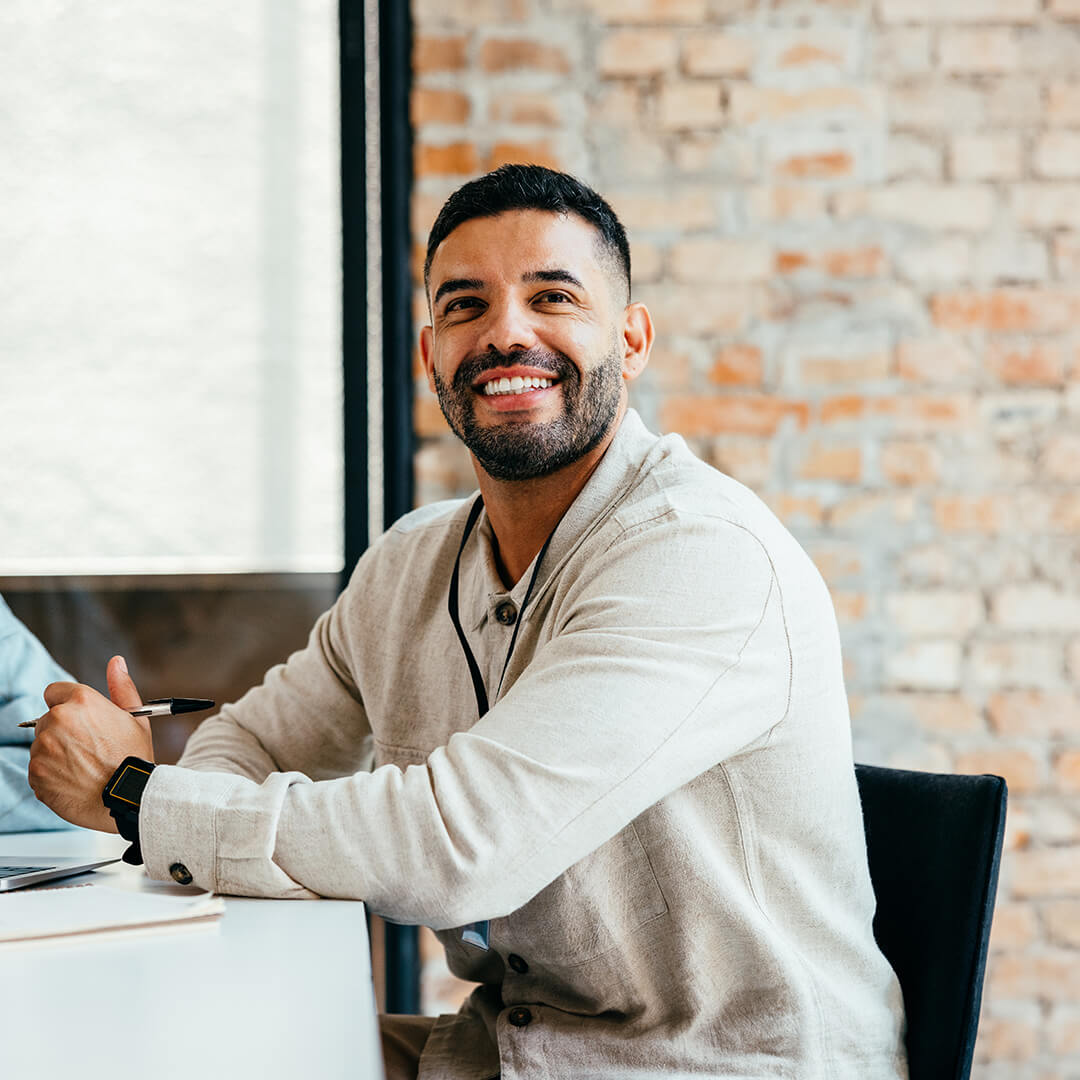 Smiling bearded man holding a pen at a meeting table in the office